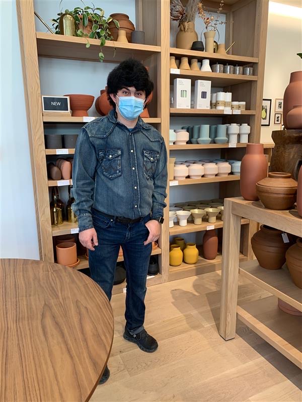 Young man in face mask standing in housing goods retail store.