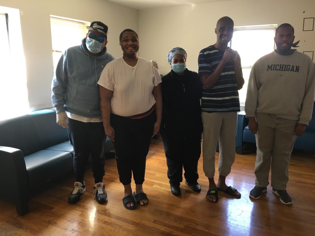 Nurse wearing a mask standing with people she supports at Birch's 52nd Street Residence