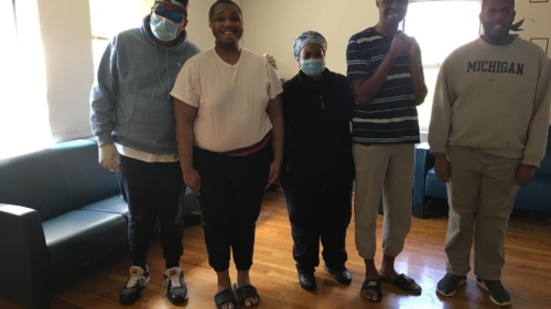 Nurse wearing a mask standing with people she supports at Birch's 52nd Street Residence